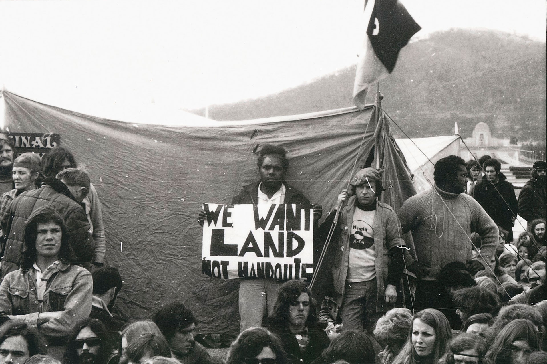 <p>Alan Sharpley (holding the sign) and John Newfong (far right) at the Aboriginal Tent Embassy in Canberra</p>
