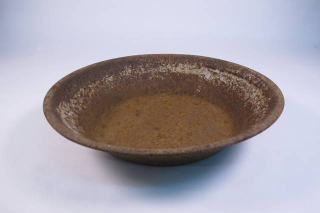 A brown coloured heavily rusted circular metal gold panning pan.