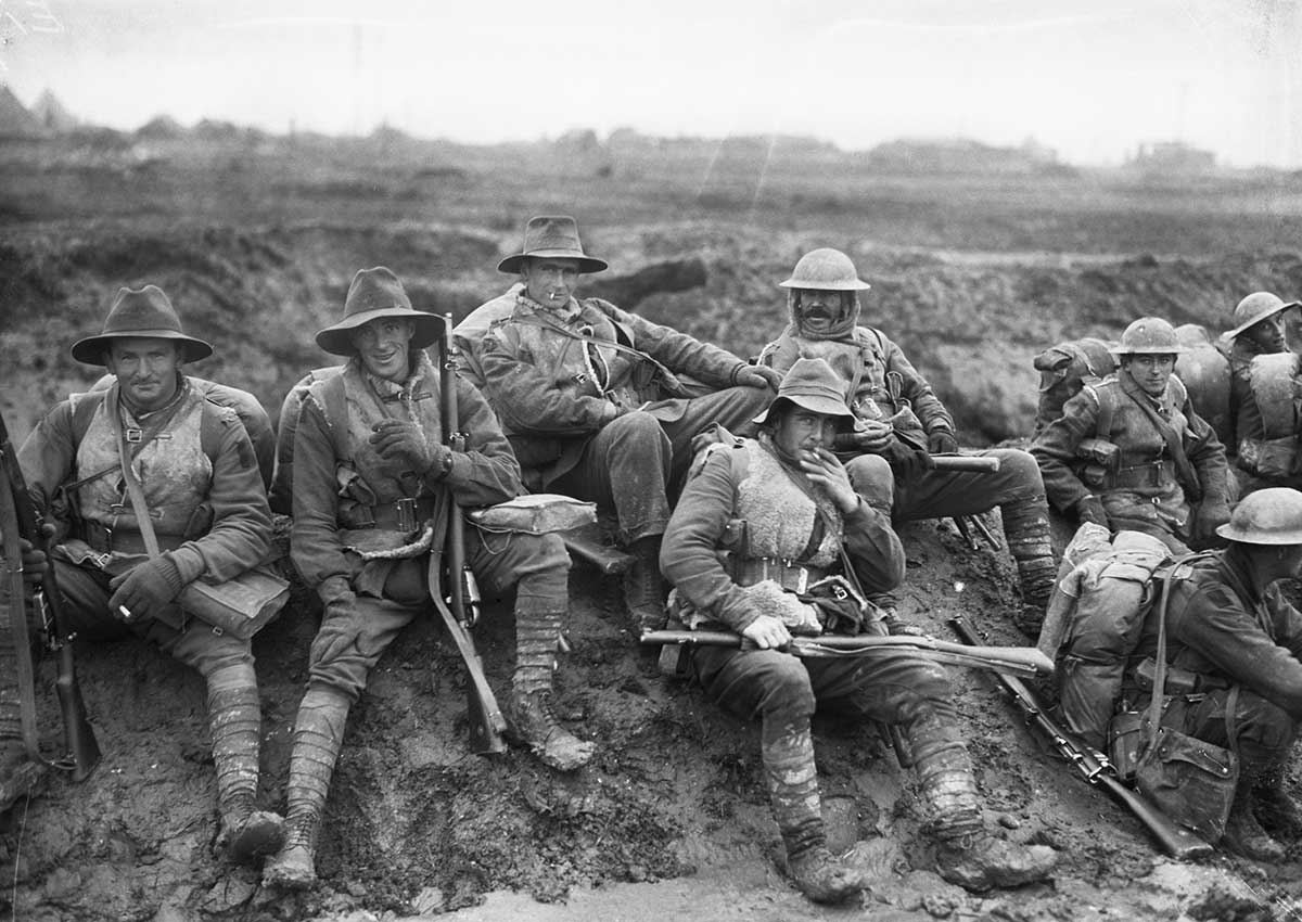 Black and white photograph of Australian soldiers resting on a muddy slope.