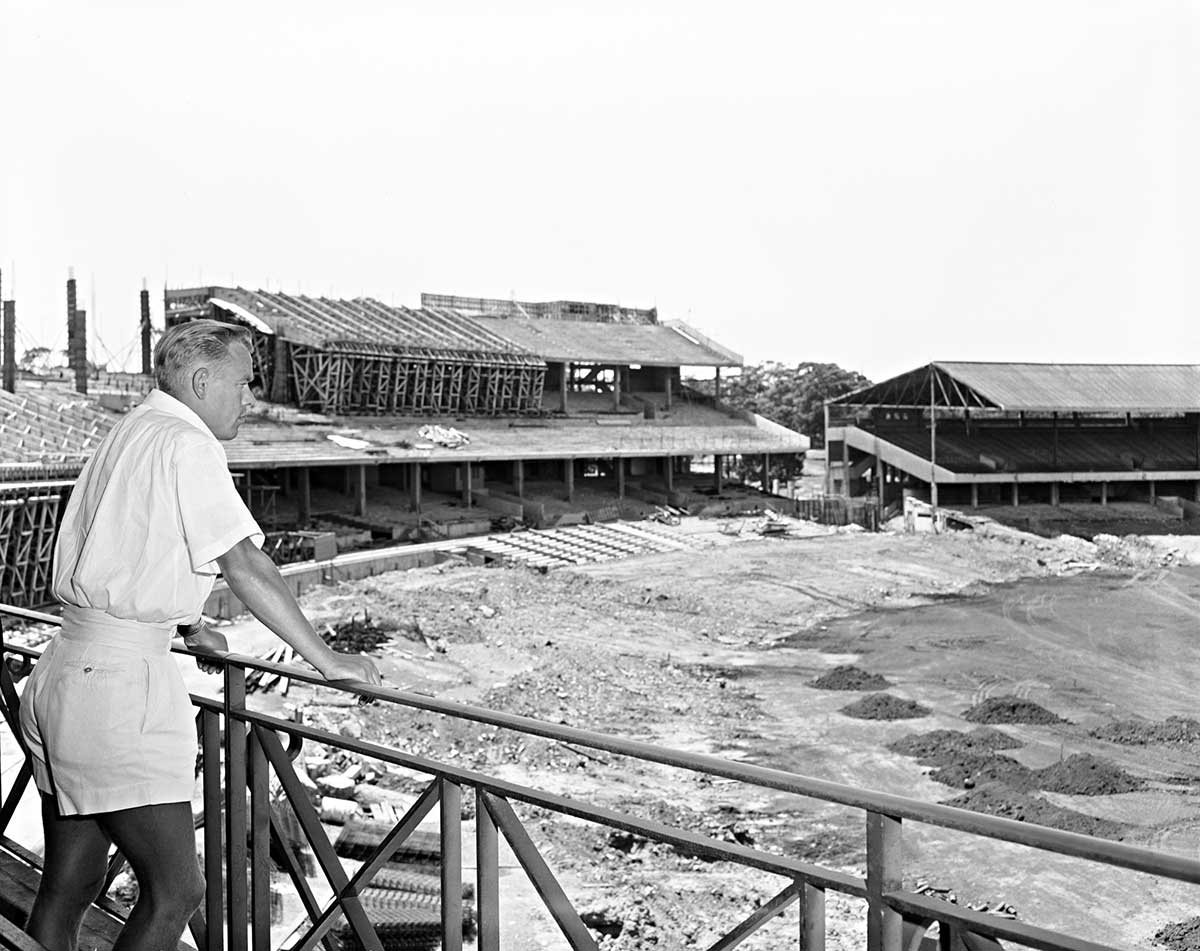 A man looks out from the stands over the MCG construction site. What is now grass is sand and dirt.