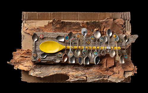 A photograph of an artwork made from teaspoons, bark and cardboard.