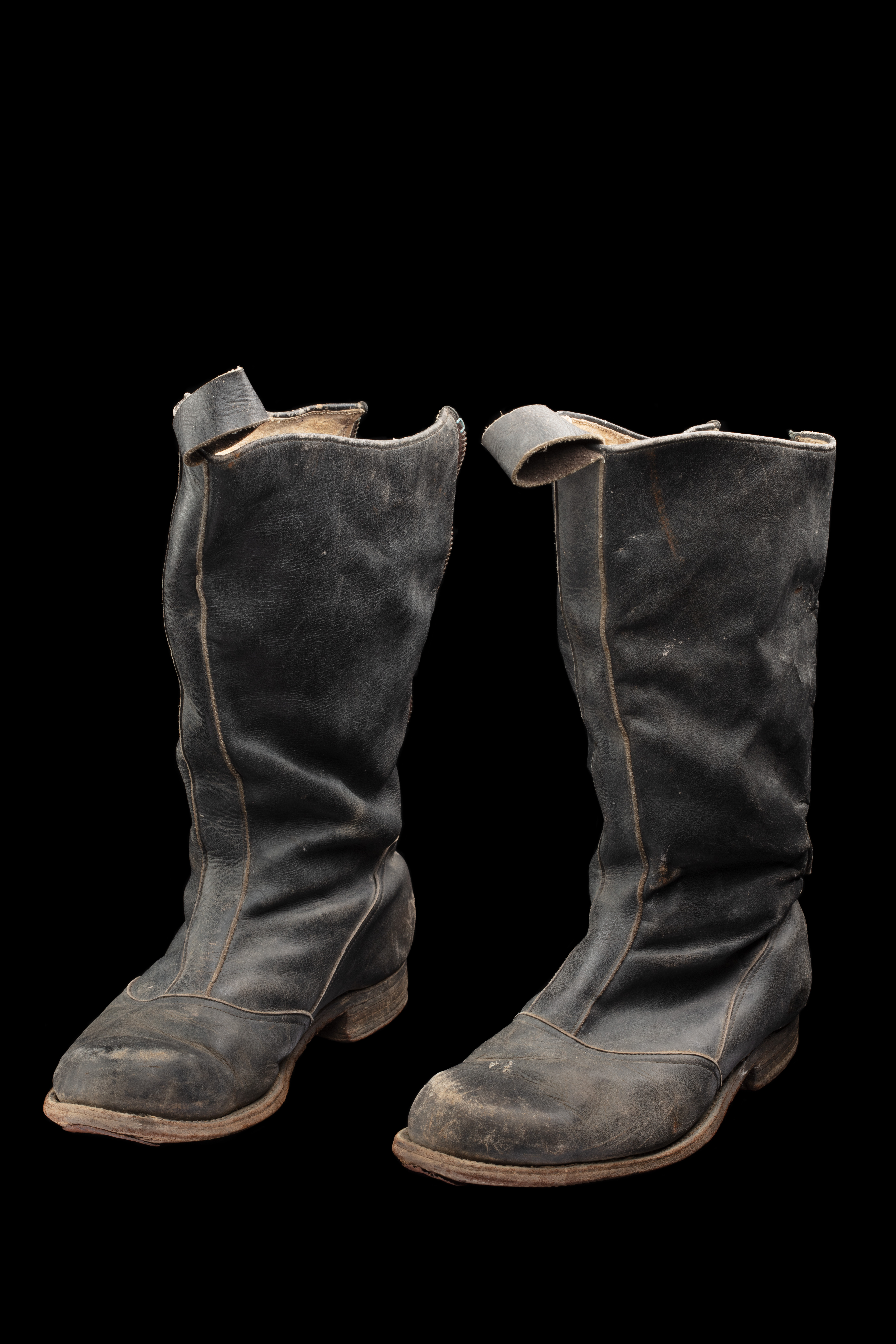  A pair of black leather steel capped work boots. Text written in black marker pen on the interior edge on of each boot reads, 'FRED HARRISON / SNOWY RIVER SCHEME'. The left boot has a yellow piece of wire through a leather loop at the front. Both boots were held together with a green piece of wire.