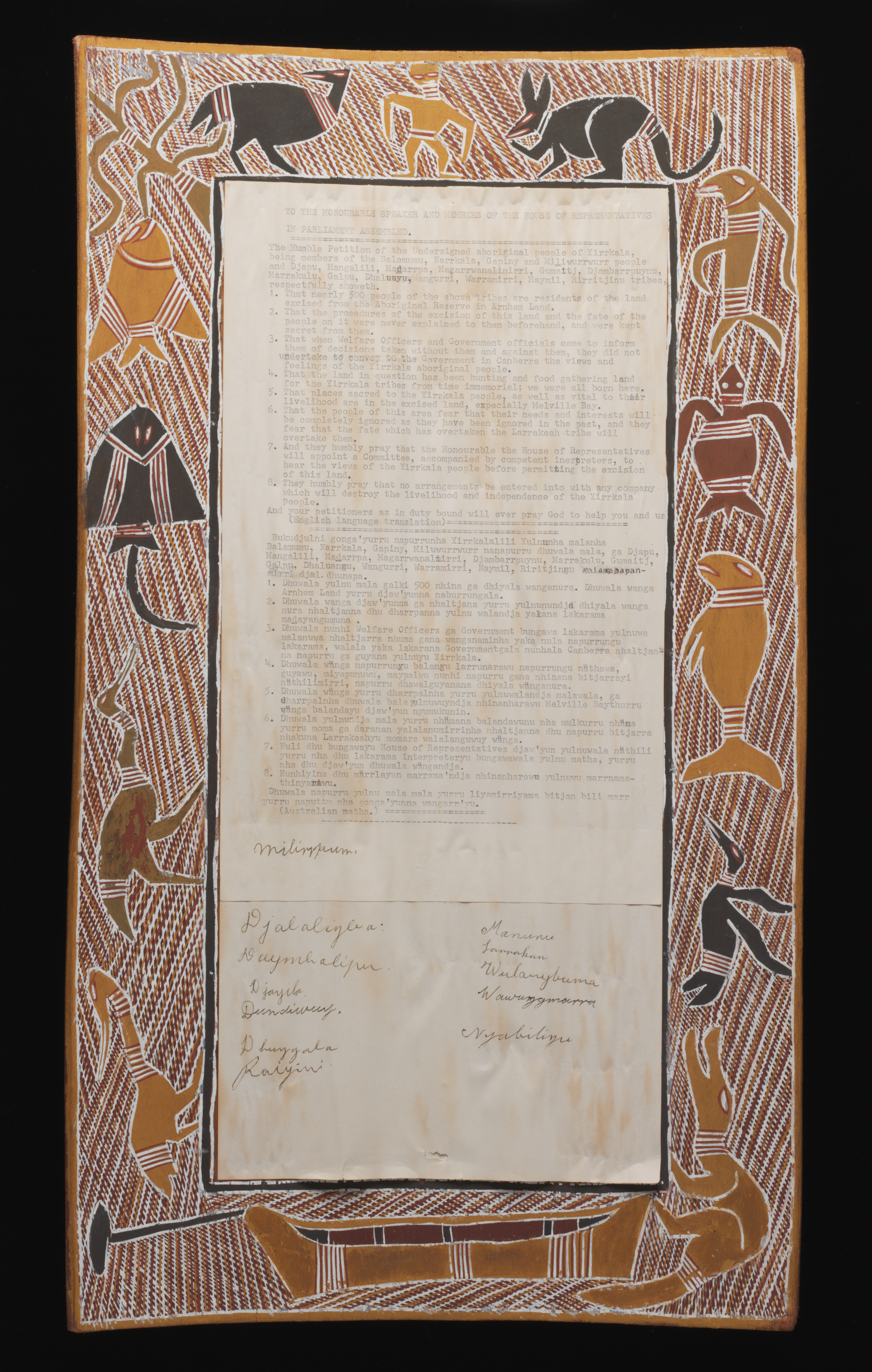 A rectangular bark painting that forms a border around a typed petition on paper. The bark is painted with yellow, white, brown, red, and black ochre. The border depicts a man, a kangaroo, a turtle, a dugong, a crocodile, a stingray, fish, several birds, and a canoe on a background of cross-hatching. 