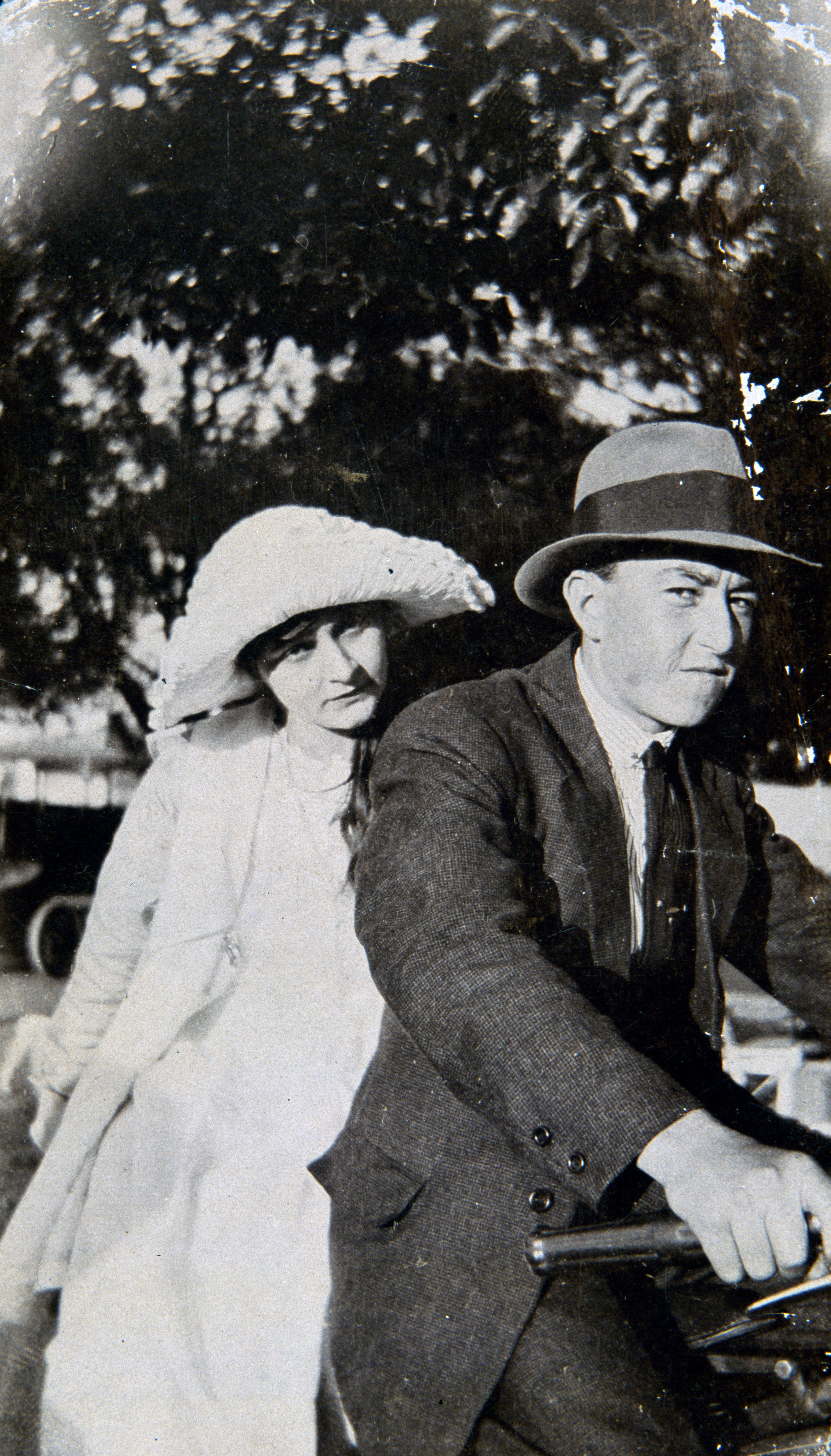 Black and white photo of two people on a bike.