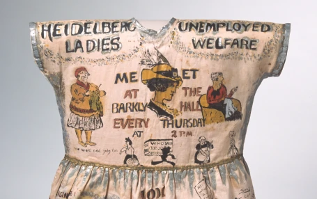 'Heidelberg Dress' – girl's fancy dress garment, hand-painted with cartoons and caricatures showing the work of the Heidelberg Unemployment Bureau, 1932. 